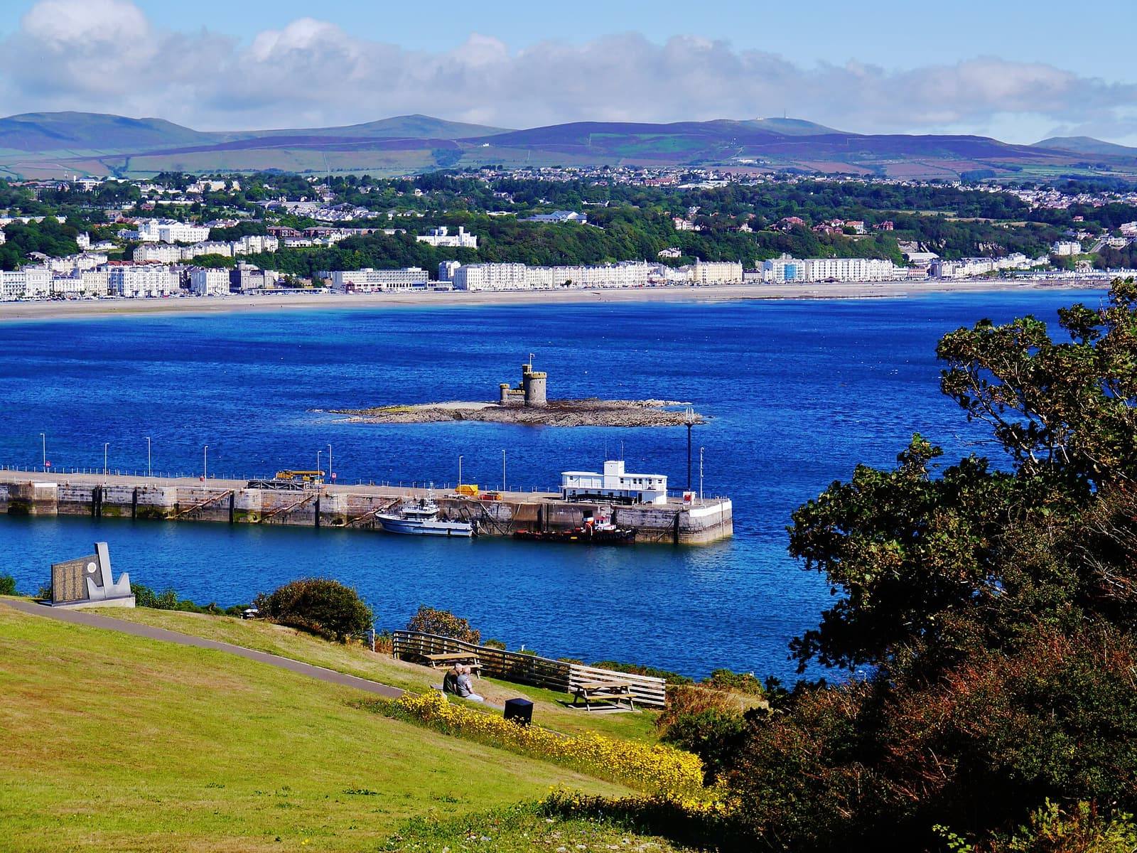 Douglas harbour's breakwater and the Tower of Refuge, with the town's seafront and the hills behind.