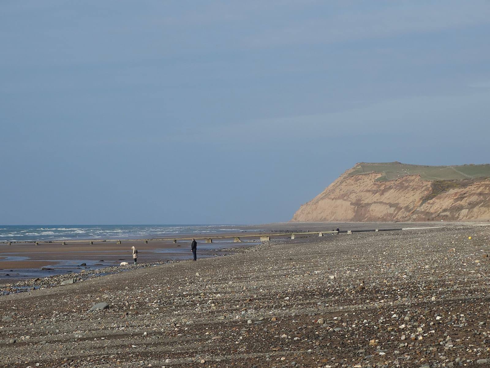 The long shingle and sand beach at Kirk Michael stretching towards the sandy cliffs of Orrisdale Head on a calm evening.