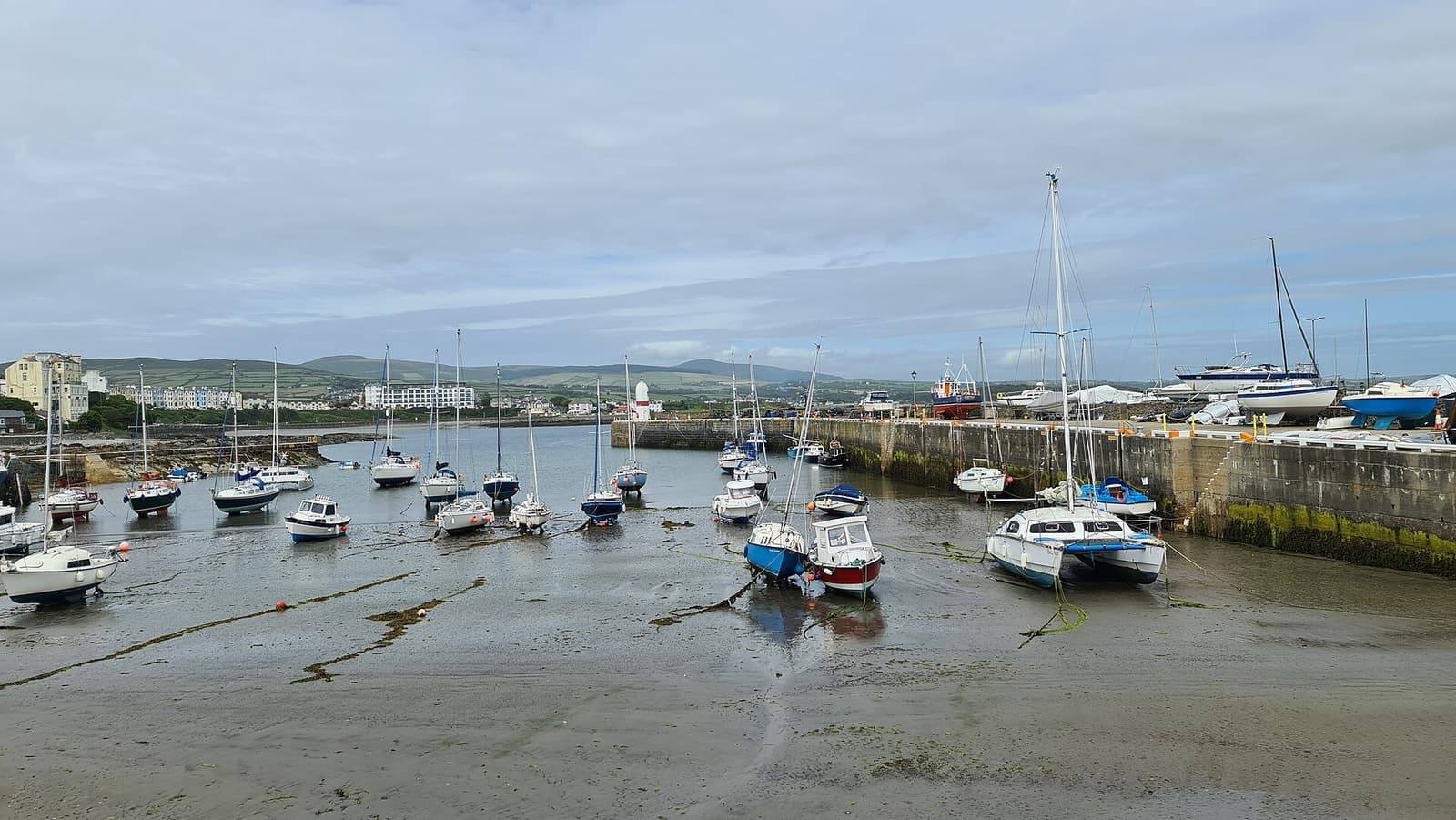 Small boats resting on the sand of Port St Mary's inner harbour beside the breakwater.