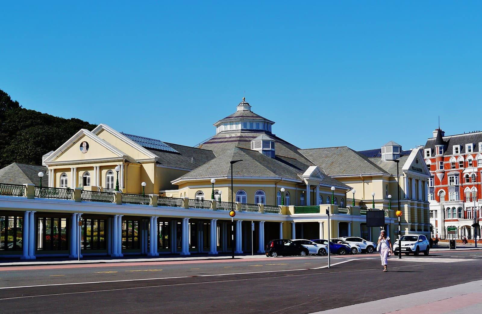 The cream-coloured Villa Marina with its domed roof and long colonnade along Douglas promenade, with wooded hills behind.